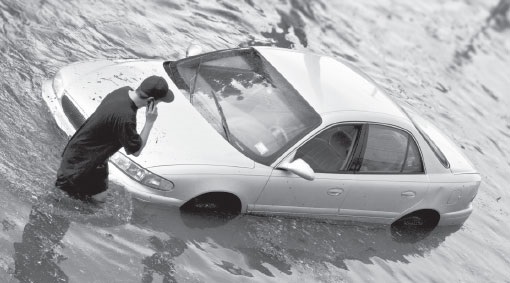Man standing in water with car submerged